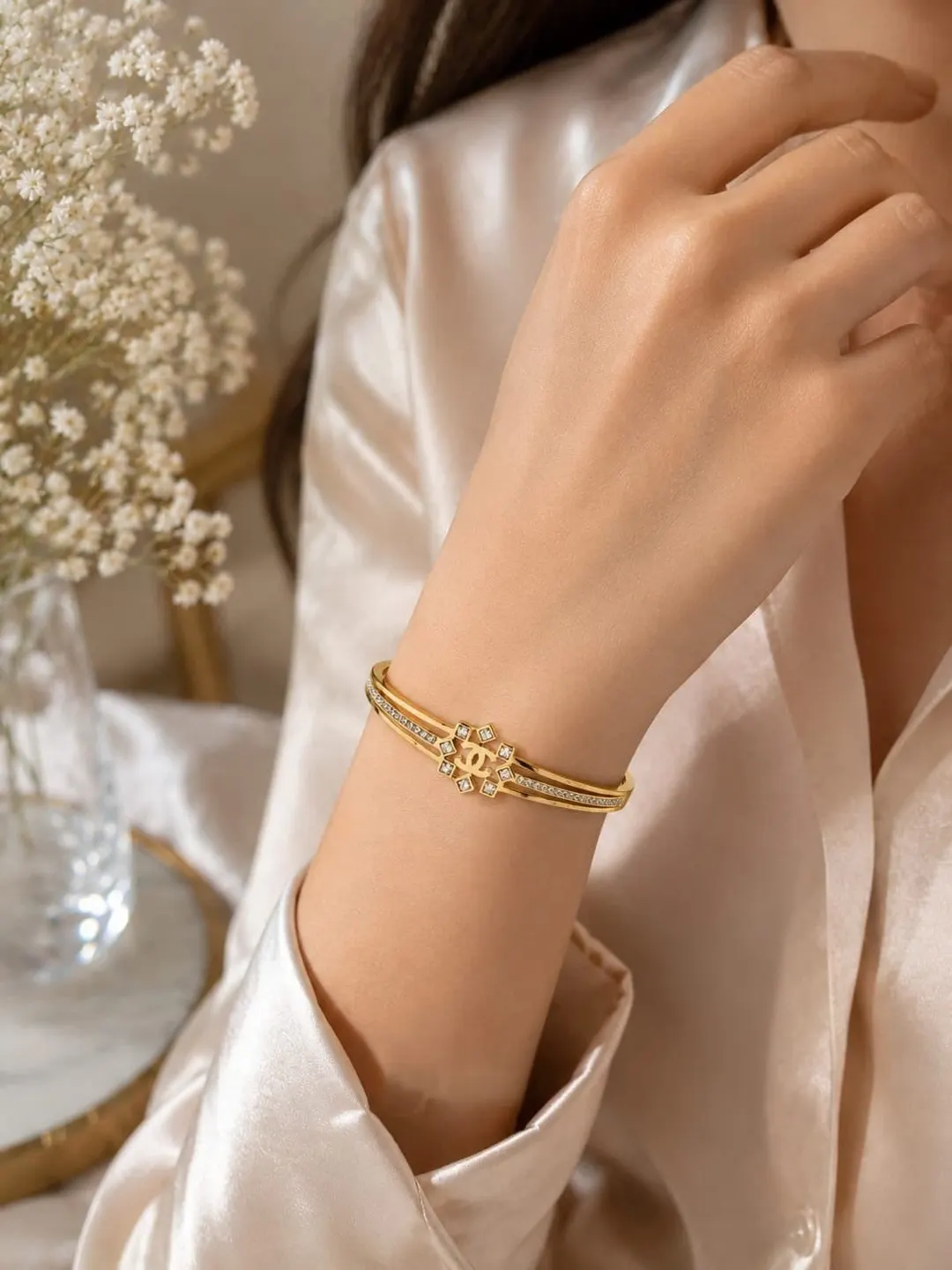 CHANEL GOLD TONE CYRSTAL EMBELLISHED HINGED BRACELET.