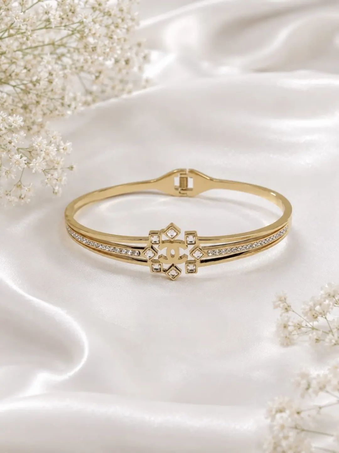 CHANEL GOLD TONE CYRSTAL EMBELLISHED HINGED BRACELET.