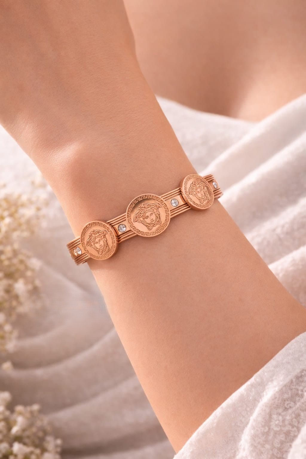 STRIKING ROSE GOLD  TONE FINISH ACCENTED WITH SIGNATURE  MEDUSA COIN MEDALLIONS, CRYSTAL EMBELLISHMENTS AND A CONVENIENT HINGED CLOSURE.