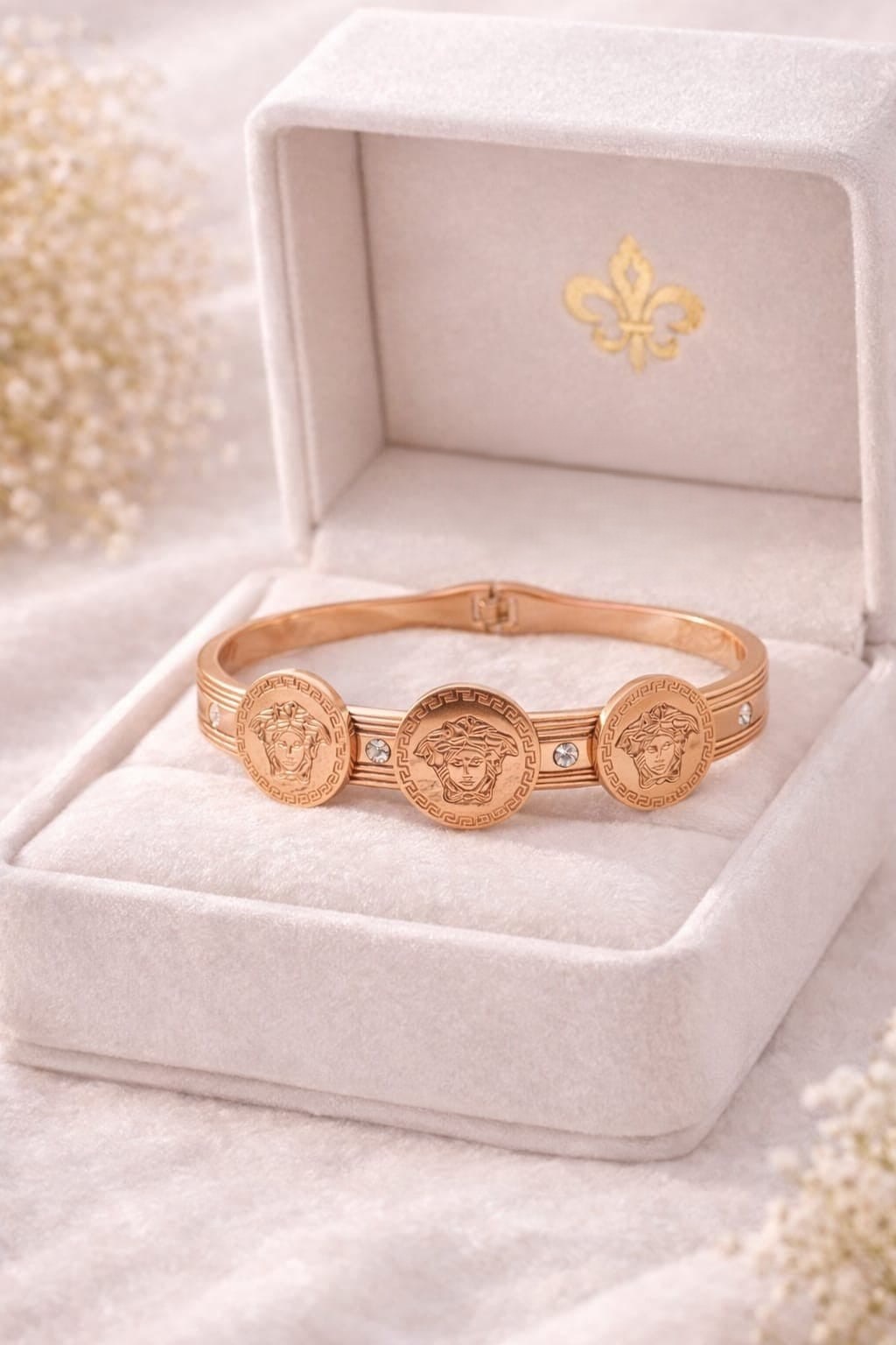 STRIKING ROSE GOLD  TONE FINISH ACCENTED WITH SIGNATURE  MEDUSA COIN MEDALLIONS, CRYSTAL EMBELLISHMENTS AND A CONVENIENT HINGED CLOSURE.