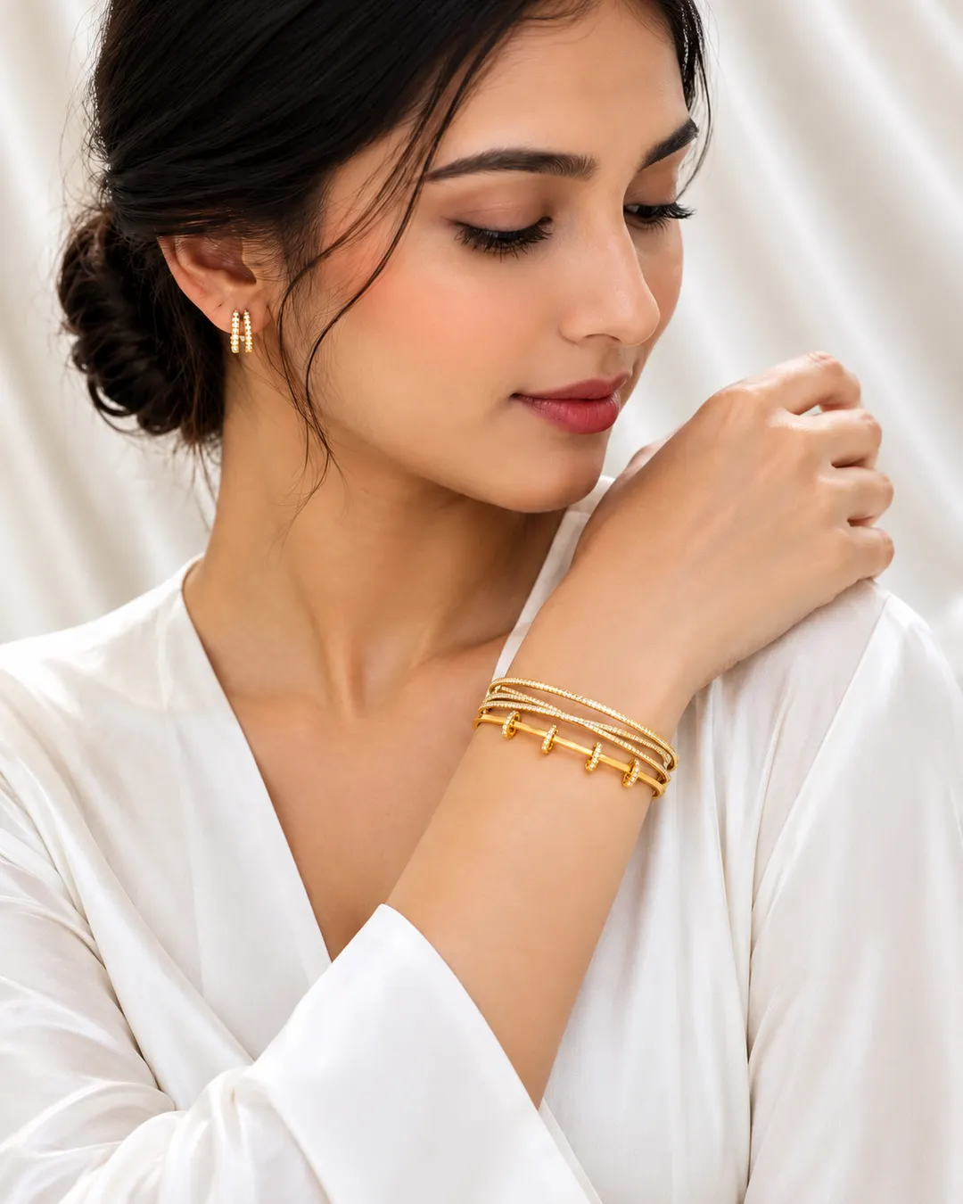 GOLD TONE CROSSOVER CUFF WITH SLIDING RING CHARMS.
