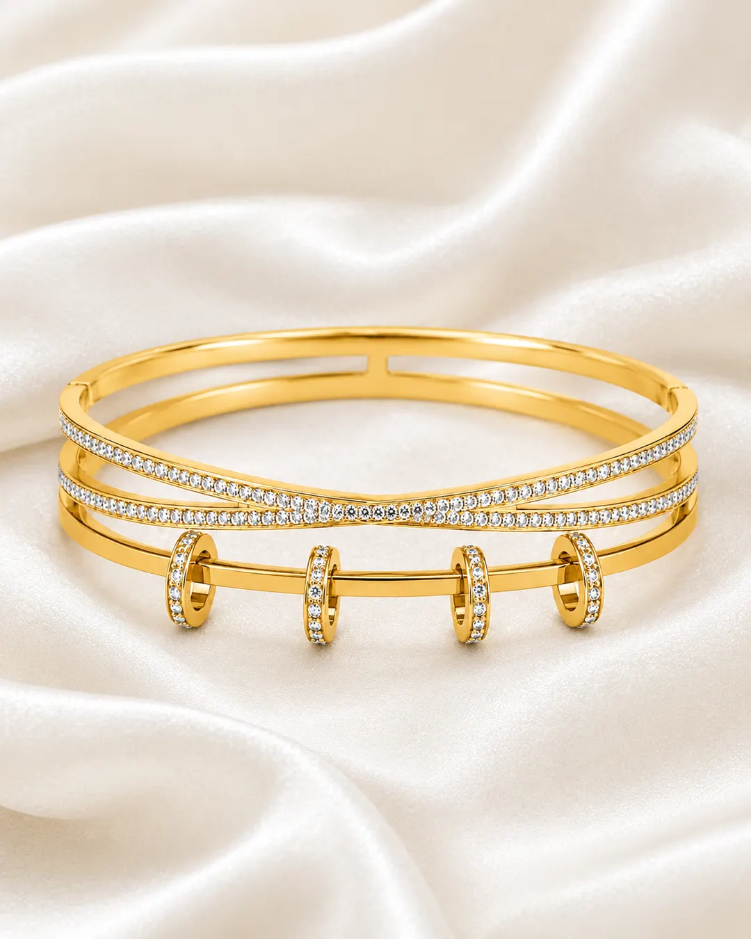 GOLD TONE CROSSOVER CUFF WITH SLIDING RING CHARMS.